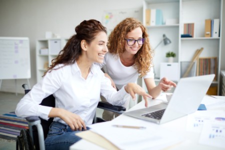 EY - Two women smiling at something on computer screen